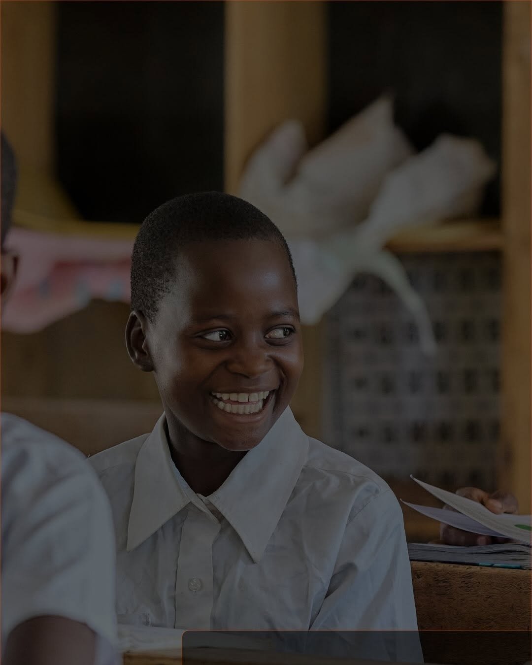 A schoolboy laughing in a classroom in a village in Mbeya
