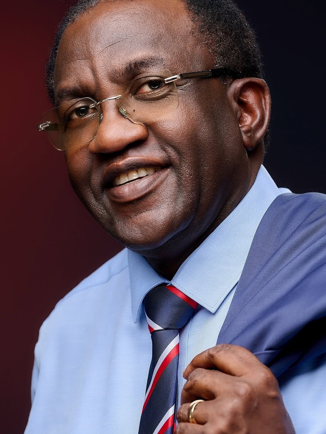Portrait of a smiling man in a blue shirt against a red background