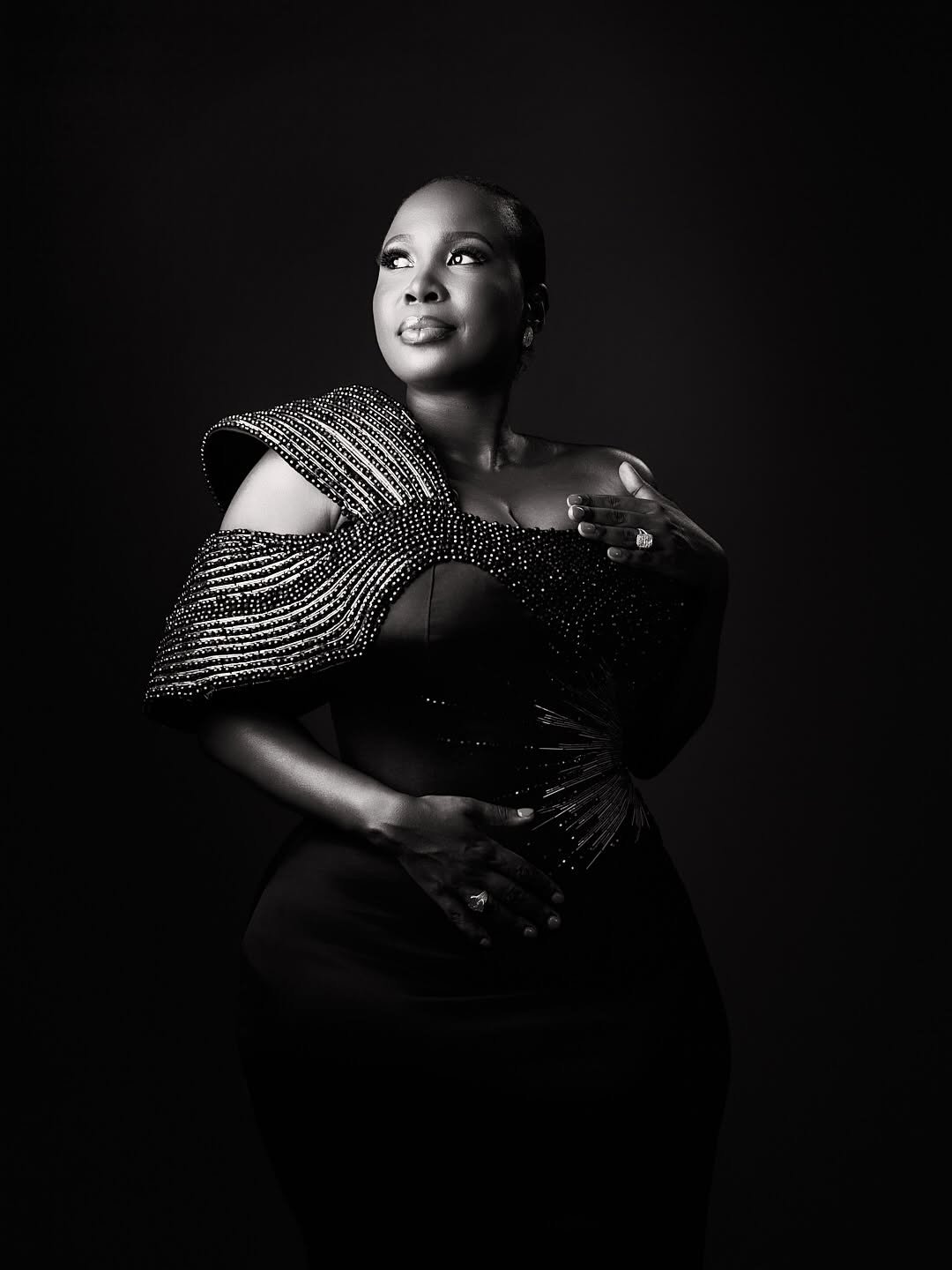 Studio portrait of a woman in a black dress with a sculpted shoulder