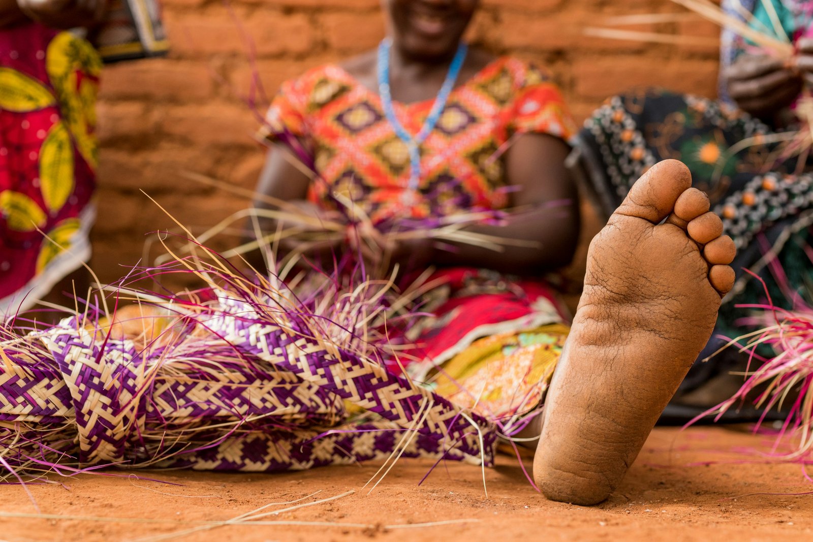 Women weaving baskets from dyed grass